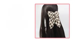 Détail d'une pince à cheveux nœud à carreaux avec rubans montrant la texture du tissu