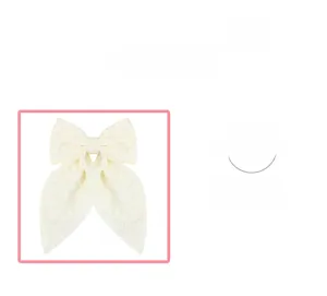 Detailed view of a cream-colored bow hair clip with elegant floral jacquard texture