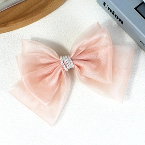 Elegant large light pink organza bow hair clip with pearl center decoration on a white surface