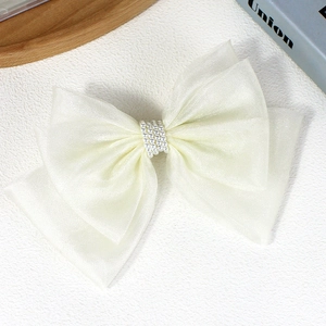Macro detail of multi-layer tulle bow hair clip with elegant pearl center and texture