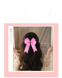 Detailed close-up of a pink handmade grosgrain ribbon bow hair clip with long tails