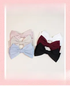 Detail view of five assorted satin bow hair clips in white, pink, blue, red, and black