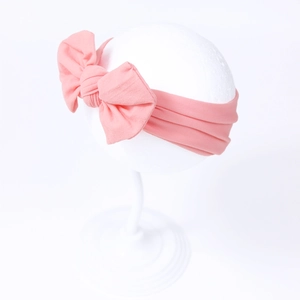 Pink nylon baby headband with a large handmade bow on a white foam mannequin head display