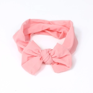 Pink nylon baby headband with large knit bow knot on clean white background