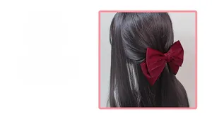 Detail of burgundy satin bow hair clip with multi-layer design on long hair