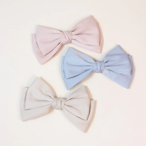 Elegant matte bow hair clips set in pink, light blue, and grey with spring clip design