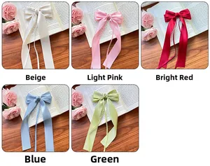 Détails des barrettes à nœuds en satin beige, rose, rouge, bleu et vert sur du bois