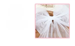 Gros plan d'un nœud de mariée en tulle blanc avec perles brillantes sur plateau