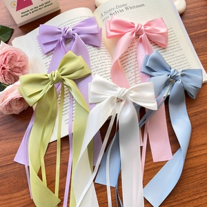 Nœuds pour cheveux en satin élégants avec de longs rubans en cinq tons pastel sur un livre