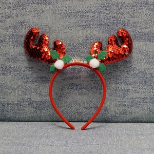 Detail of red sequined reindeer antlers and green leaves on a festive headband