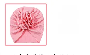 Detail of pink waffle knit baby turban hat featuring a large soft petal flower accent