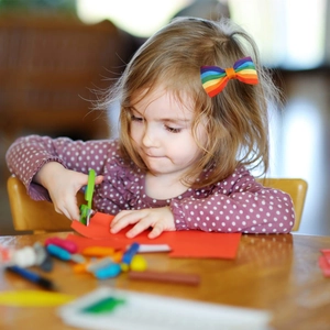 Rainbow ribbon hair bow clip worn by a young girl during creative craft activities