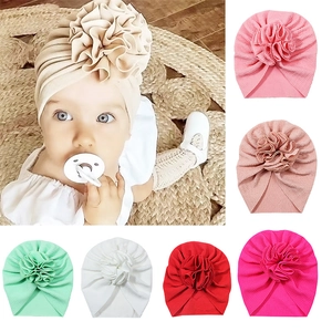 Soft pleated baby turban hat with a large handmade flower, shown in 7 pastel colors