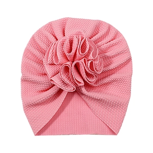 Pink waffle knit baby turban hat featuring a large layered pleated flower design