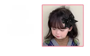 Close-up of a handmade black satin bow hair clip worn by a girl for styling