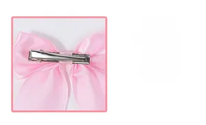 Close-up of pink satin bow hair clip showing secure silver metal alligator clip attachment