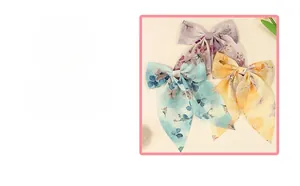 Détail de barrettes à fleurs en mousseline en violet, bleu et jaune avec de longs rubans