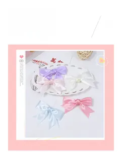 Close-up of five macaron-colored satin bow hair clips in a decorative white plate