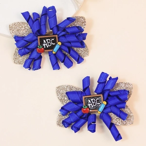 Detail of school-themed bow hair clips with glitter wings and ABC chalkboard charms