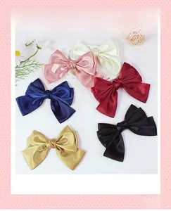 Detailed view of layered satin bow hair clips in multiple colors on a floral backdrop