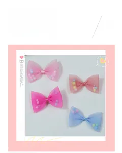 Detail of mesh bow hair clips filled with colorful pom-poms in pink and blue