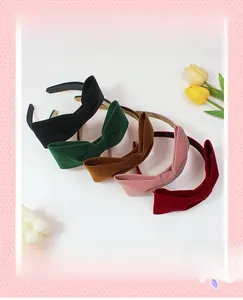 Détail de cinq serre-têtes en velours avec nœuds en noir, vert, brun, rose et bordeaux