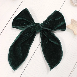 Pince à cheveux nœud en velours vert foncé sur fond de bois blanc minimaliste