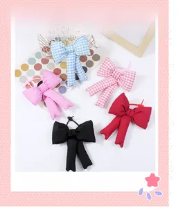 Close-up of cute padded fabric bow keychains in pink, blue, and red plaid patterns