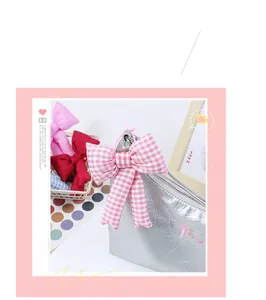 Detailed close-up of a pink checkered fabric bow charm attached to a silver shiny puffer bag