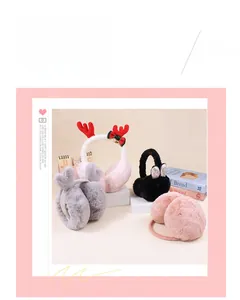 Detail of plush reindeer earmuffs with red bows, golden bells and soft faux fur texture