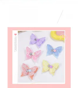 Détail de pinces à cheveux papillon en dentelle avec pompon et strass brillants