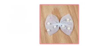 Close-up of light blue mesh bow accessory with white pearls and sequins for DIY crafts