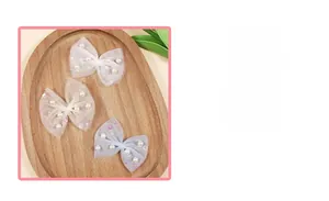 Detailed view of mesh bow hair clips with pearls and sequins in white, cream, and grey-blue