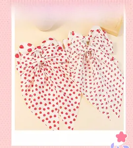 Detail of fabric bow hair clips with strawberry and cherry prints on cream base