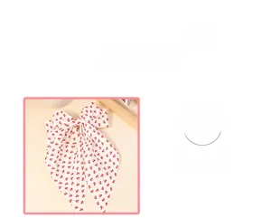 Detail of white bow hair clip featuring red cherry prints and soft fabric texture