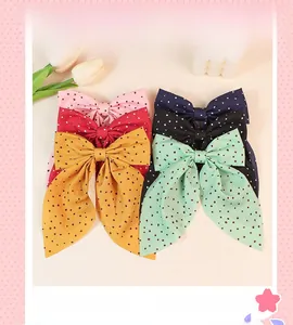 Close-up of assorted polka dot bow hair clips with long ribbons in six pastel colors