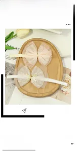 Detail of pink and cream lace mesh bow headbands with golden buckle on wooden tray