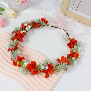 Close-up of vibrant red floral crown with small white flowers and pink ribbons