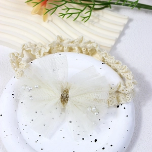 Detail view of baby lace headband with large tulle bow and elegant pearl accents