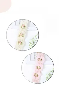 Dettaglio di fasce in pizzo fatte a mano con fiori in chiffon rosa e bianco crema tenue