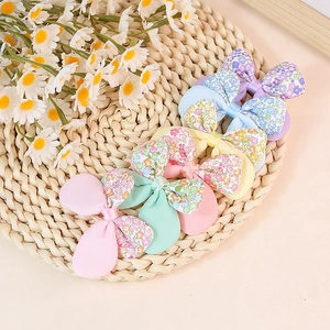 Floral patchwork bow hair clips in assorted colors on a woven mat with daisy decor
