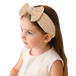Elastic knit baby headband with a large soft bow detail in apricot beige color