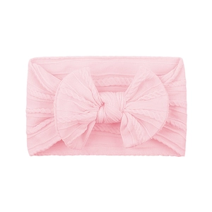 Soft pink knitted baby headband with a large cable knit bow on a clean white background