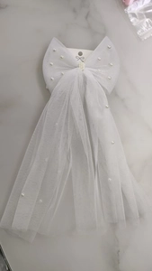 Detail shot of white mesh bow veil with faux pearl embellishments on a marble background