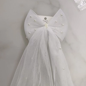 Short bridal wedding veil with white pearls and mesh bow on marble background