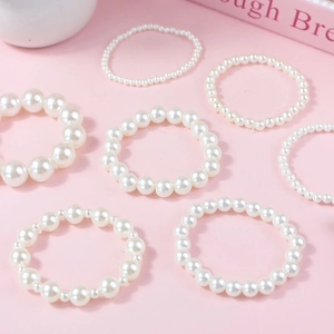Elegant 7-piece cream pearl bead bracelet set with French vintage style on pink background