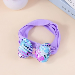 Elastic purple baby headband featuring a colorful sequin bow on a light beige background