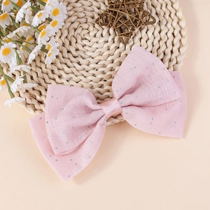 Nœud de cheveux en tissu rose avec paillettes argentées sur un tapis tressé