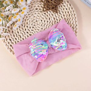 Detail of baby headband featuring large iridescent sequin bow on soft purple elastic fabric
