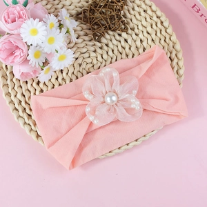 Close-up of soft pink baby headband featuring a tulle flower with a large pearl center